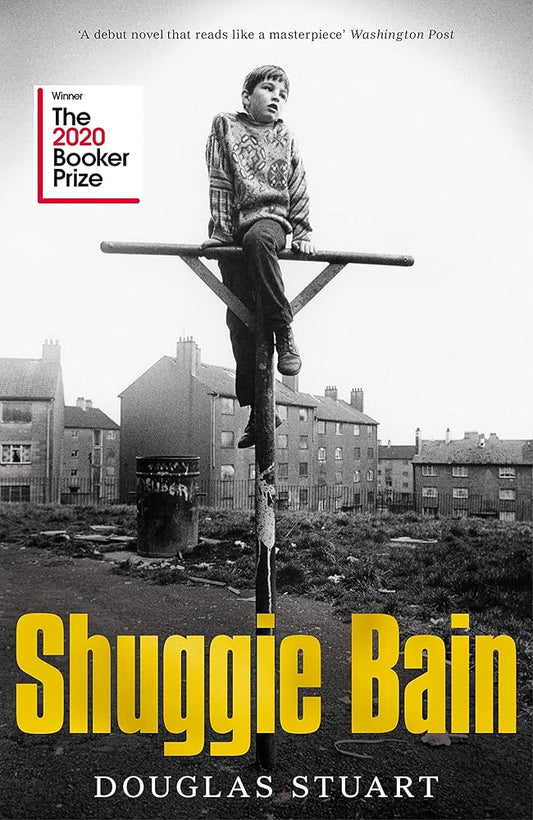 Book cover of 'Shuggie Bain' with a person on a pole and residential buildings in the background.